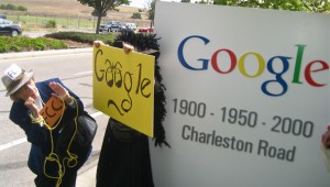 A man holds a homemade sign protesting Google
