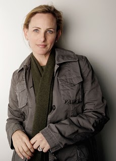 Matlin, a white woman with her hair back, wearing a scarf and jacket