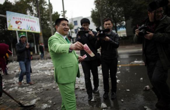 Chinese multimillionaire Chen Guangbiao gives money away to street cleaners during an event organized by him in Nanjing